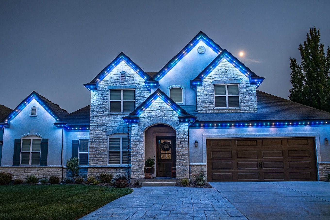 Blue permanent lights on a stone two story home